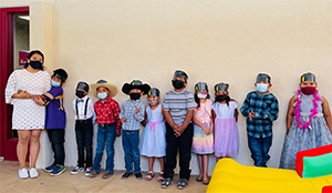 A line of happy students next to teacher wearing dress attire