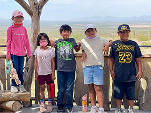 Five happy students outside in front of a beautiful desert view